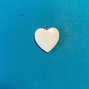 White charm, or necklace shaped like a heart. Looks to be ivory, but not sure.